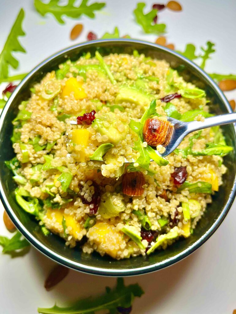 mango avocado quinoa salad in bowl with close-up of spoonful