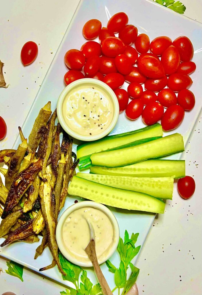 lemon garlic aioli in cups on platter with tomatoes and cucumber strips seen from above