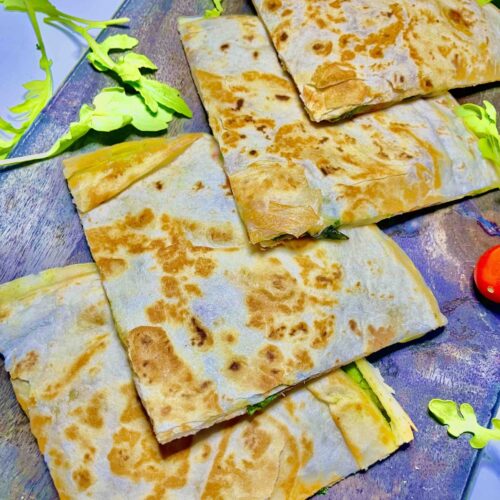 Mediterranean quesadilla cut into triangular slices on a plate