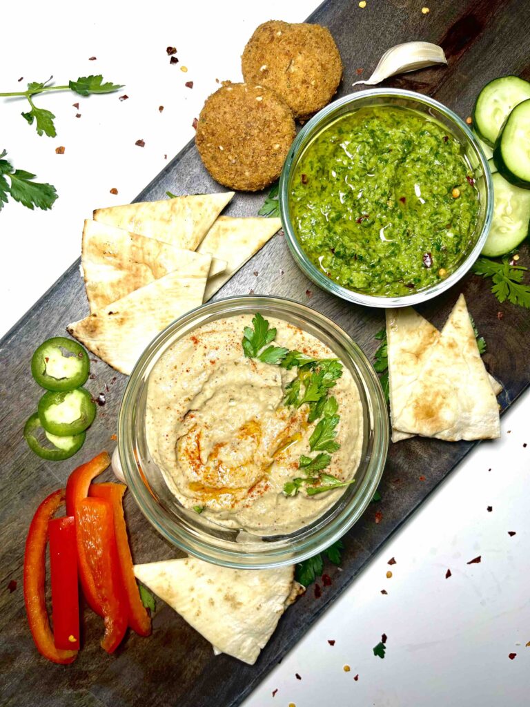 platter seen from above with baba ganoush, pesto, falafels and pita bread