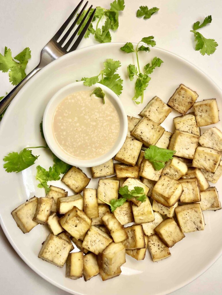 tofu cubes on plate with sauce and fork