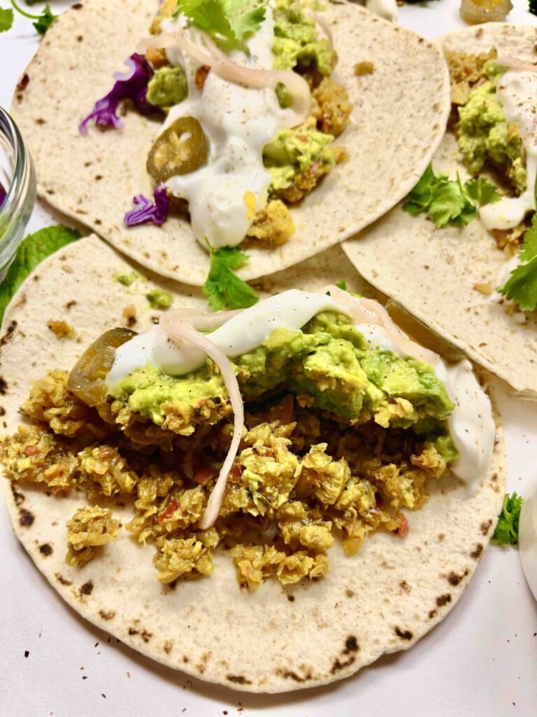 high protein vegan tacos with garnishes on tortillas