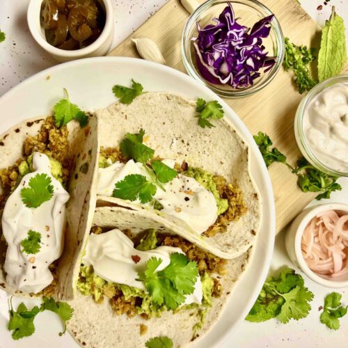 plate with several garnished tacos and other toppings around them