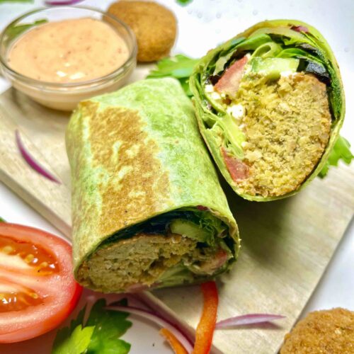 falafel wrap cut in two surrounded by ingredients