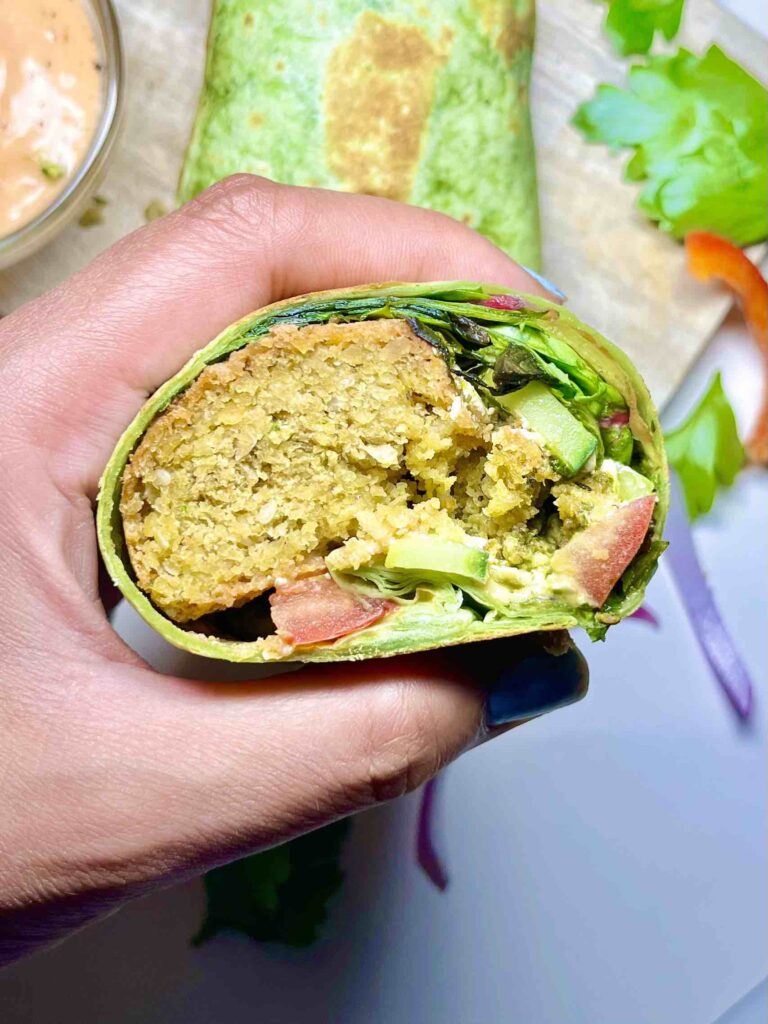 hand holding half of a falafel wrap