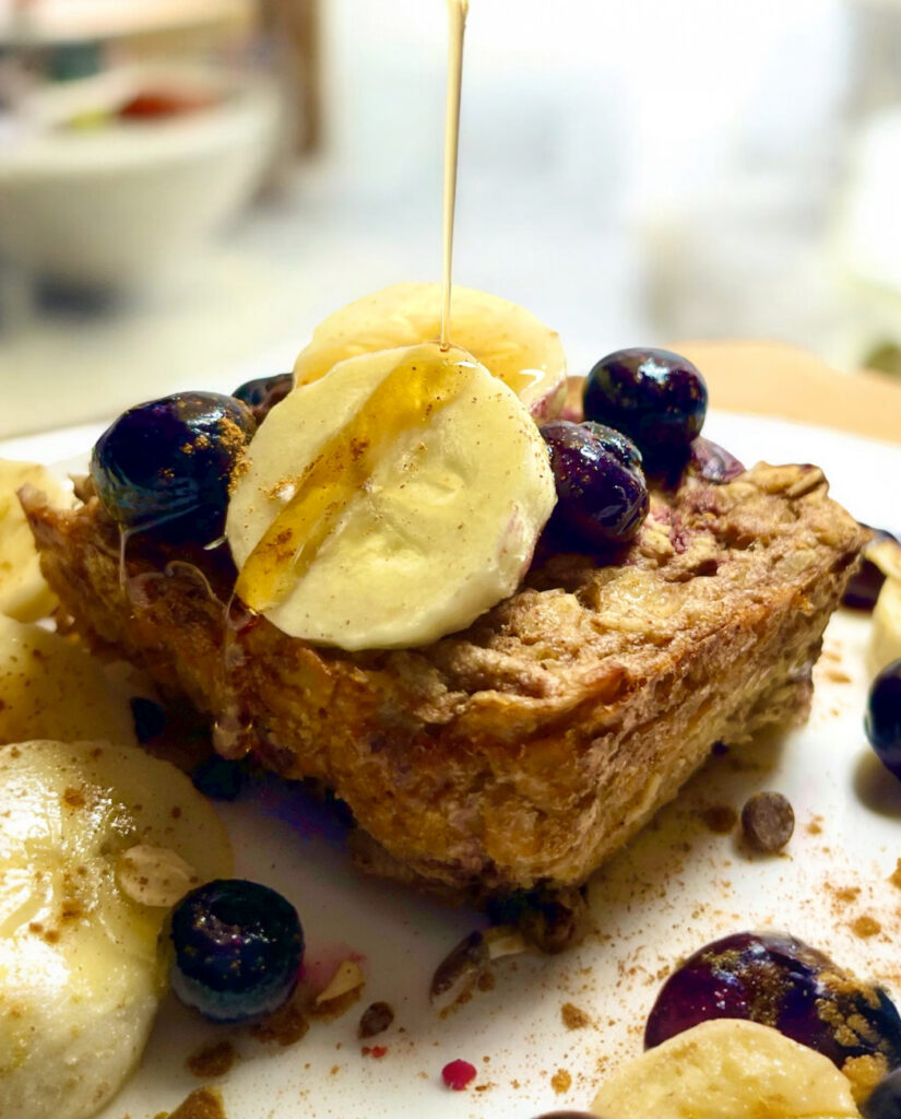 slice of vegan banana baked oatmeal on plate with syrup being drizzled over it