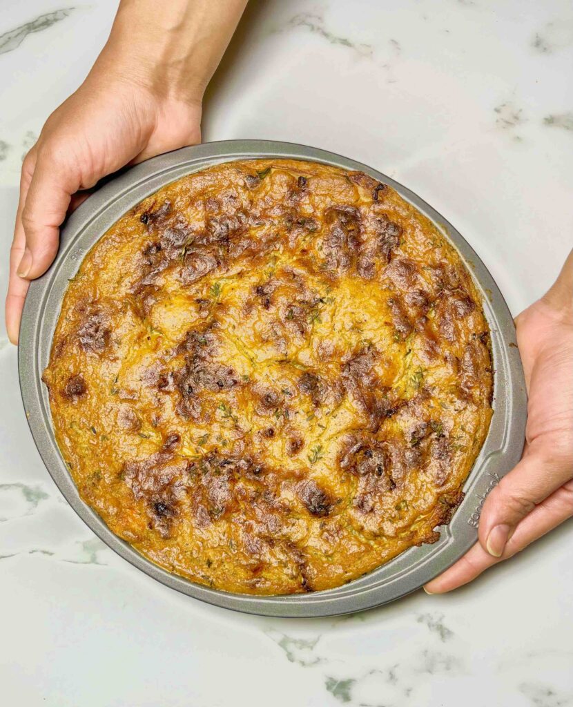 overhead shot of pan of creamy scalloped potatoes after baking held by chef's hands