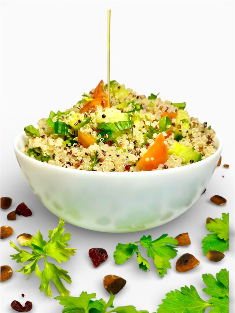 bowl of quinoa salad with maple dijon vinaigrette being drizzled onto it from above