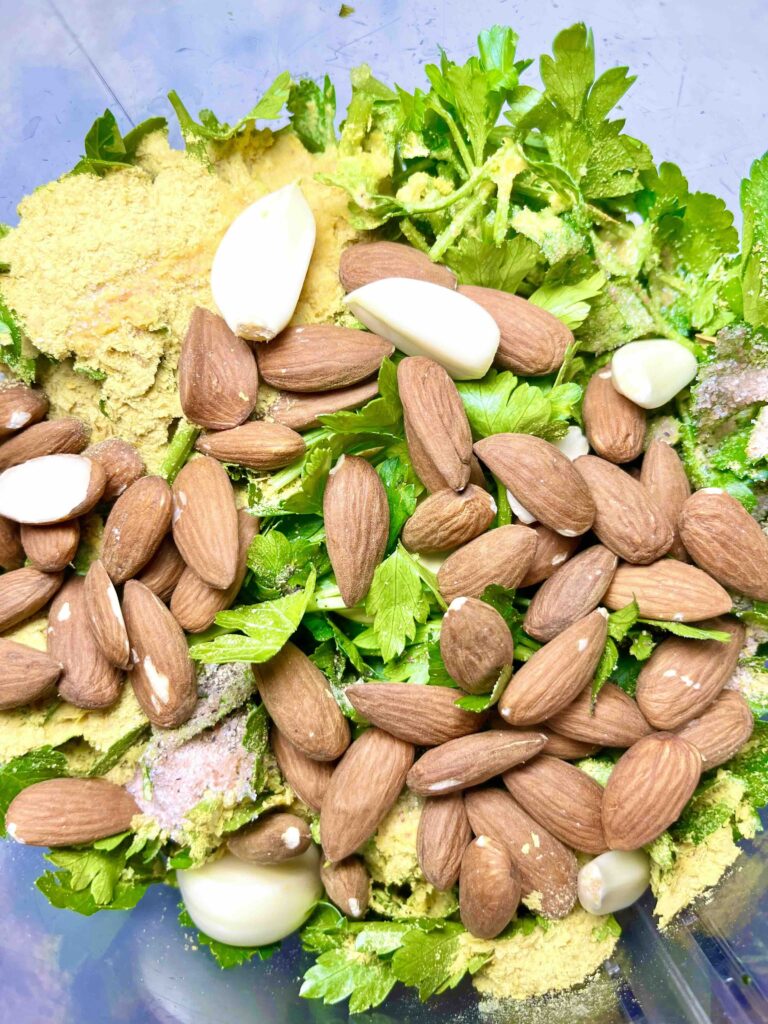 ingredients of parsley pesto: almonds, parsley, nutritional yeast and garlic seen from above