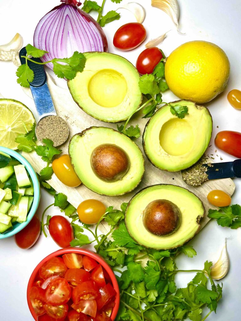 bird's eye view of salad ingredients, including sliced avocados, cherry tomatoes, and cucumber