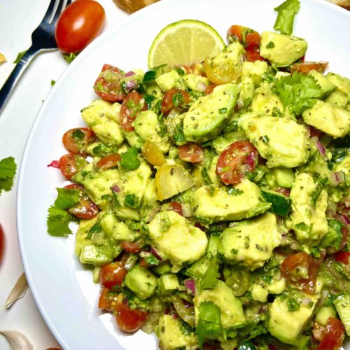 avocado salad on plate surrounded by sourdough bread and fork