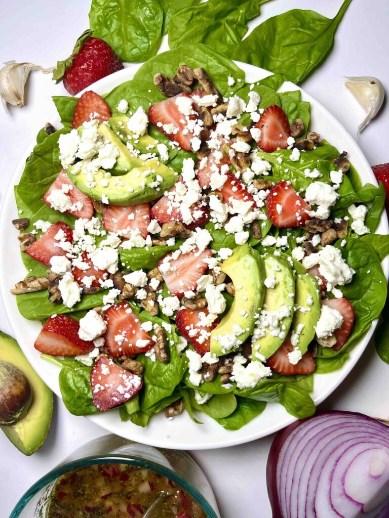 spinach strawberry salad assembled on white plate seen from above