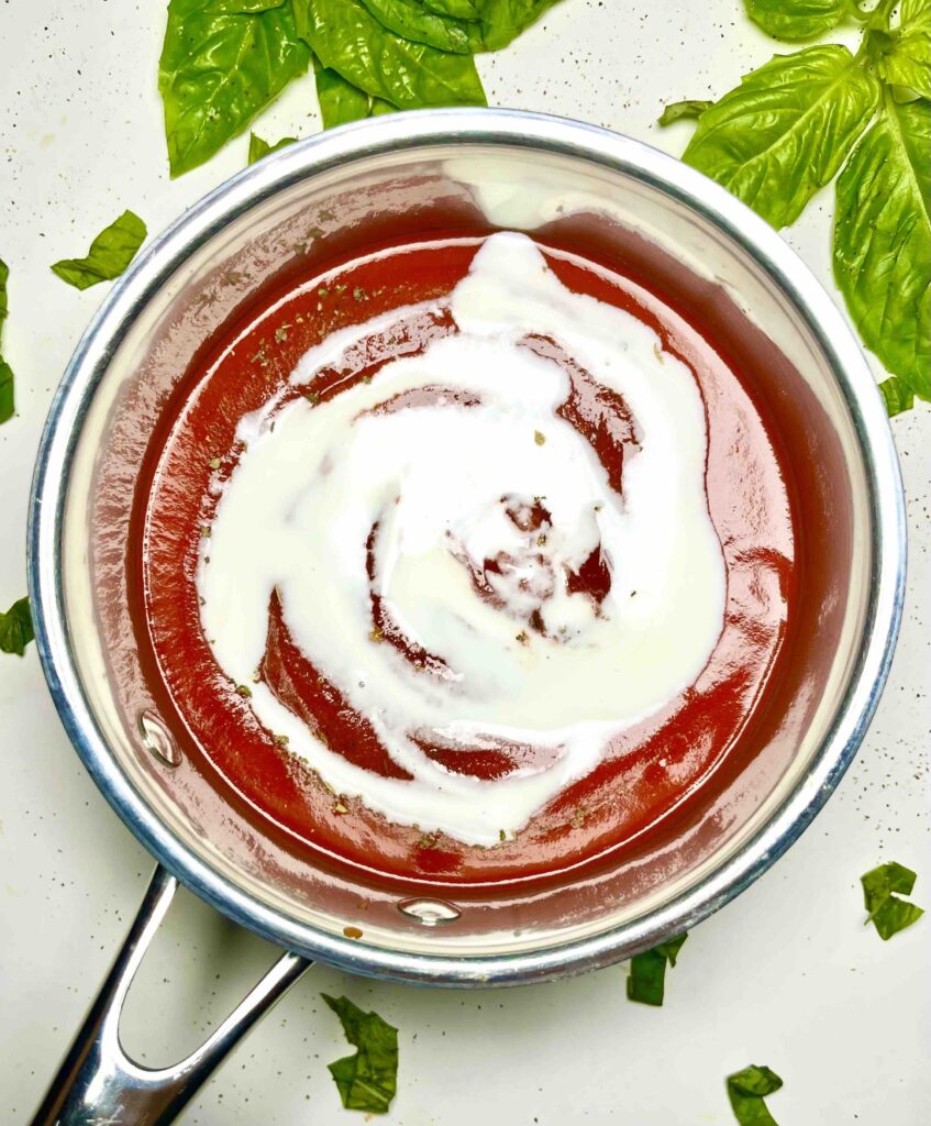 pot with tomato sauce and coconut cream before mixing and simmering seen from above