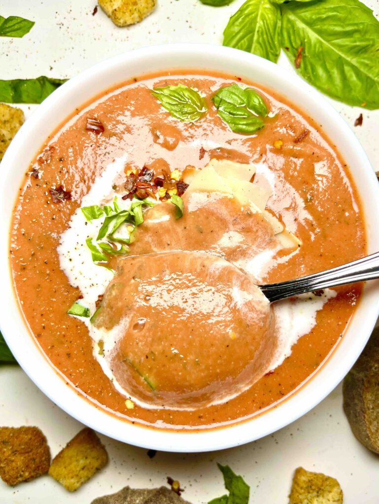 close-up of spoonful of tomato bisque with bowl in background